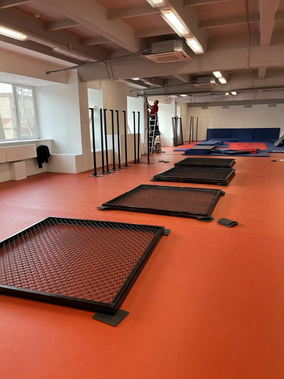 Красный ролл-мат и сетка ММА в зале РТУ МИРЭА в Москве во время монтажа