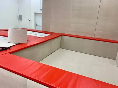 Батутная яма с бежевыми стеновыми протекторами и красными матами в гимнастическом центре Gym Family