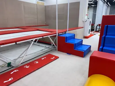 Зона батутов с синими поролоновыми ступенями и красными матами в гимнастическом центре Gym Family