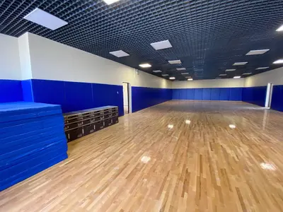 Синие протекторы по периметру зала Академии Михайлова, сложенные маты и оборудование