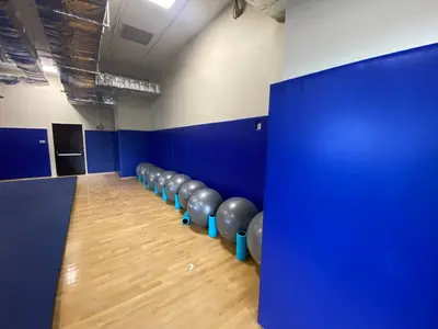 Узкий зал Академии Михайлова с синими протекторами на стенах и серебристыми фитболами