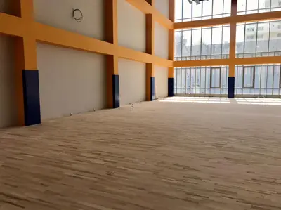 Синие защитные протекторы на колоннах в школьном спортзале с деревянным полом