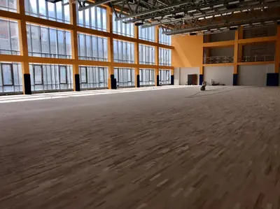 Общий вид школьного спортзала с синими протекторами на колоннах у панорамных окон