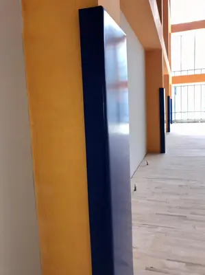 Крупный план синего защитного протектора на жёлтой колонне в школьном спортзале