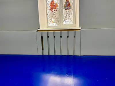 Крупный план серых протекторов вокруг окна и протектора на радиатор, синий мат на полу