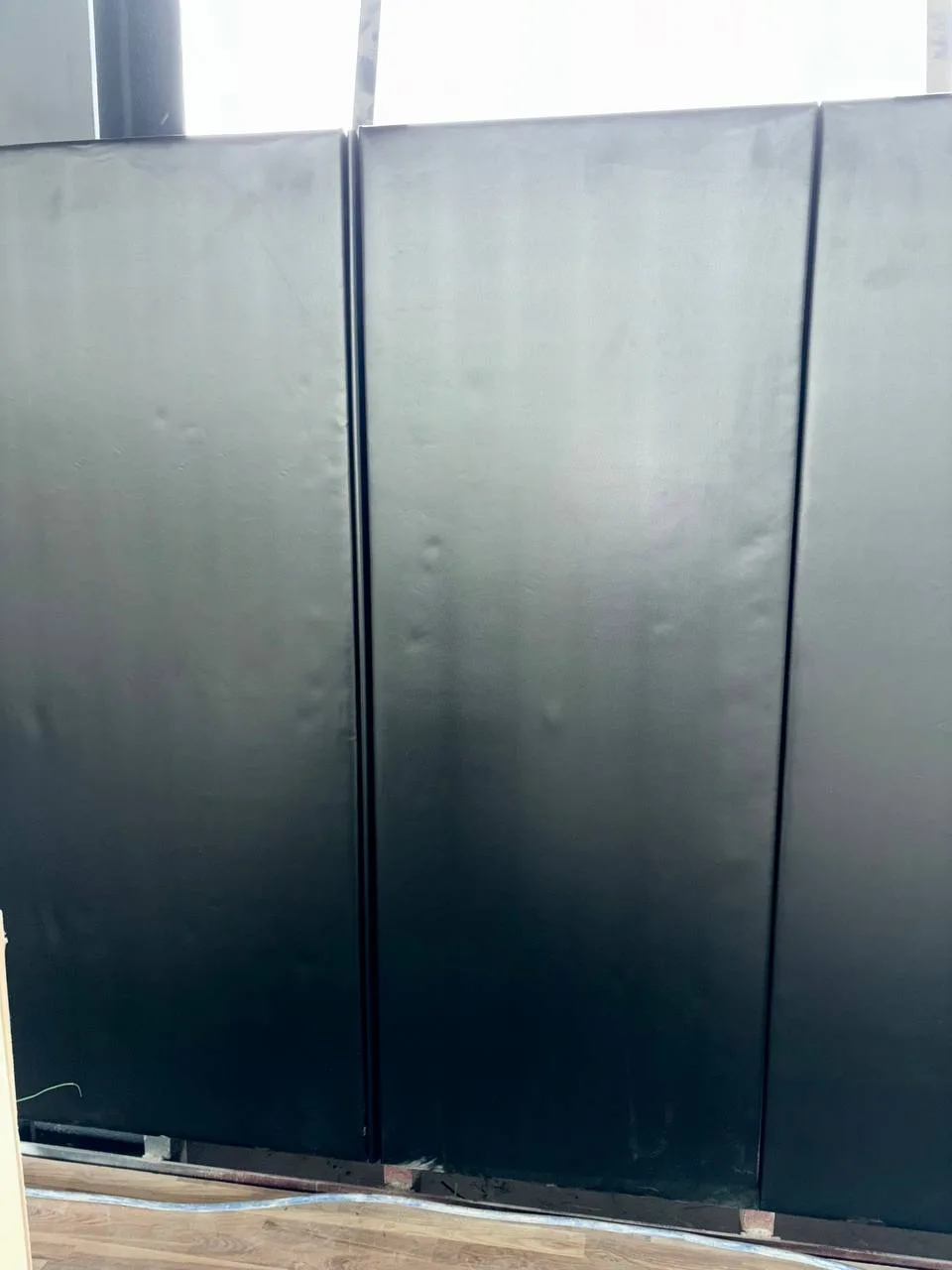 Крупный план: чёрный стеновой протектор с ПВХ-покрытием на стене спортзала