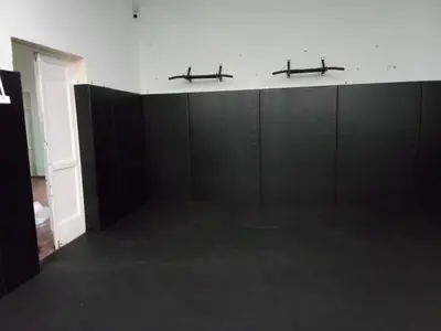 Стена зала с черными протекторами и настенным турником, черный ролл-мат на полу