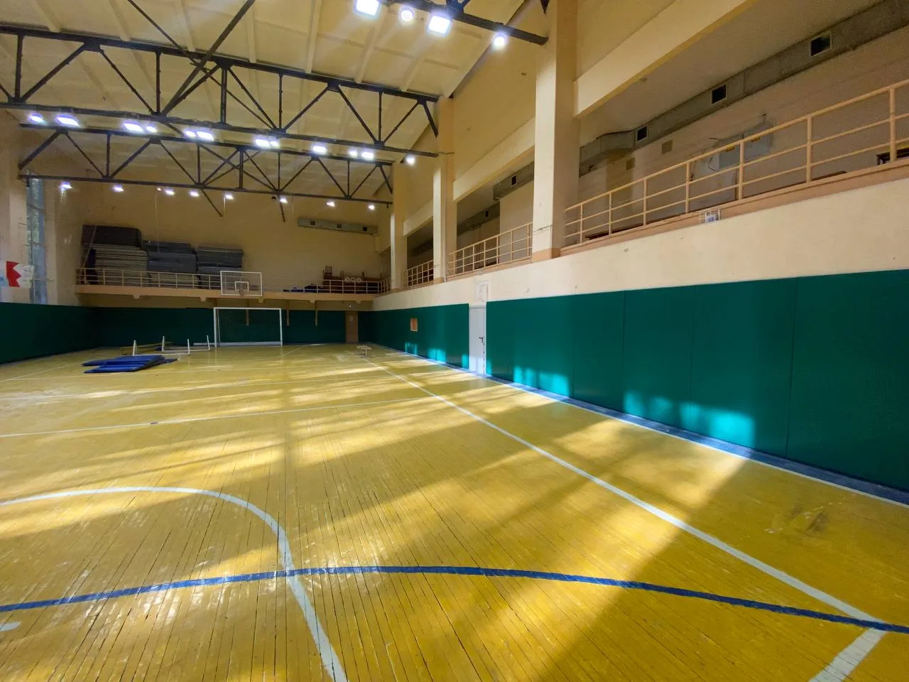 Темно-зеленые стеновые протекторы в большом зале СК Торпедо Владимир с паркетным полом и балконом