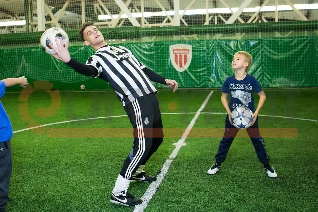 Зелёные стеновые протекторы в крытом футбольном манеже, дети играют в футбол