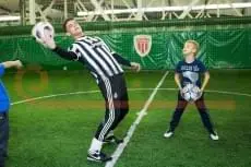 Зелёные стеновые протекторы в крытом футбольном манеже, дети играют в футбол