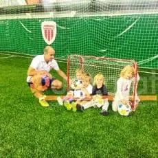 Тренер с детьми у мини-ворот на фоне зелёных стеновых протекторов Жуковка