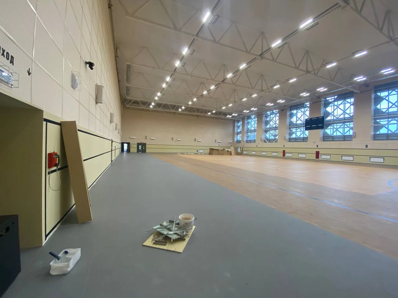 Работа по установке черных стеновых протекторов вдоль стены спортивного зала с видимыми ОСП-панелями