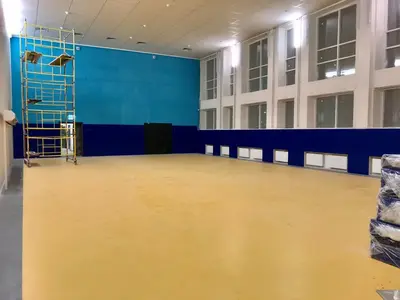 Синие стеновые протекторы на стене школьного спортзала, строительные леса, бирюзовая стена