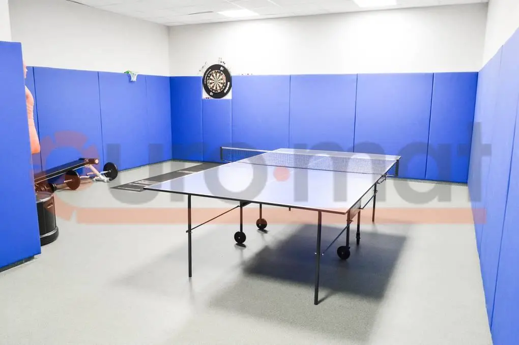 Синие стеновые протекторы по периметру зала с теннисным столом и мишенью для дартс