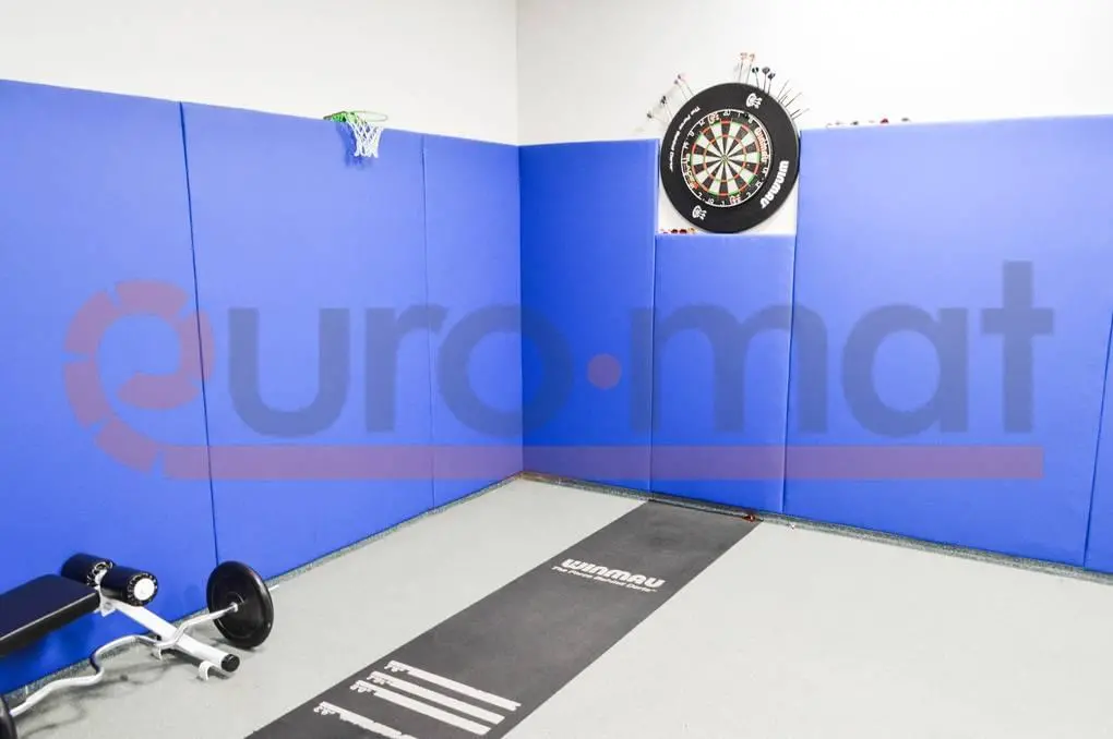 Синие стеновые протекторы в углу зала с мишенью для дартс и баскетбольным кольцом