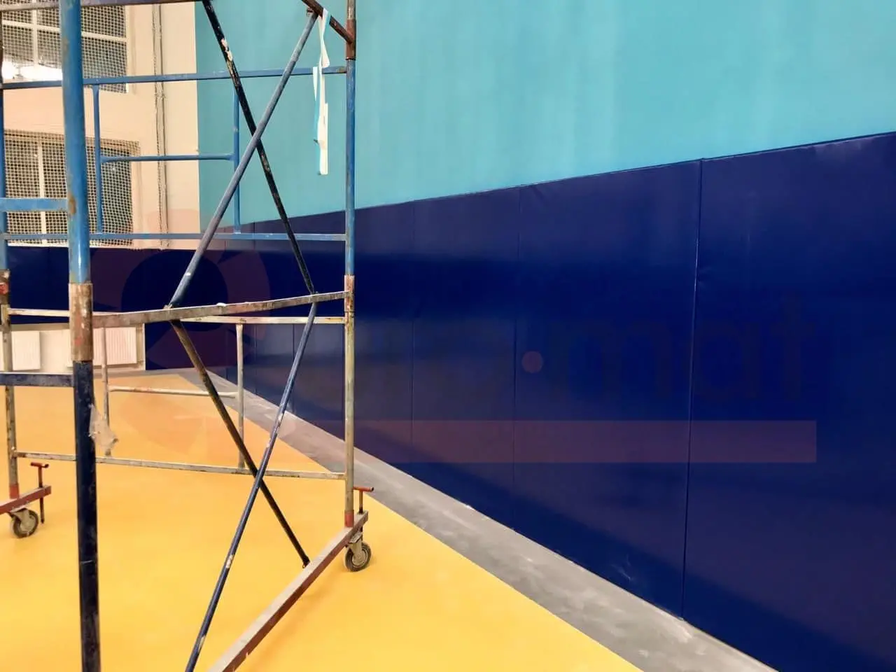 Тёмно-синие стеновые протекторы крупным планом в зале единоборств, строительные леса у стены