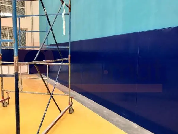 Тёмно-синие стеновые протекторы крупным планом в зале единоборств, строительные леса у стены