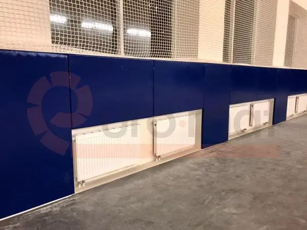 Тёмно-синие стеновые протекторы с вырезами под радиаторы, крупный план угла зала единоборств