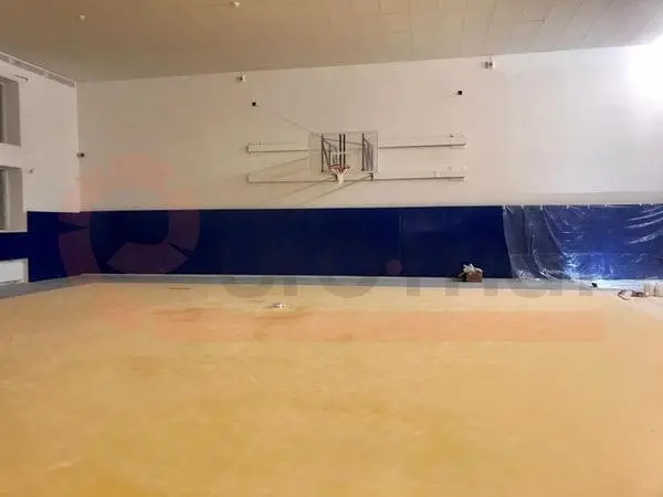 Синие стеновые протекторы под баскетбольным щитом в зале единоборств, жёлтый пол, монтаж завершён