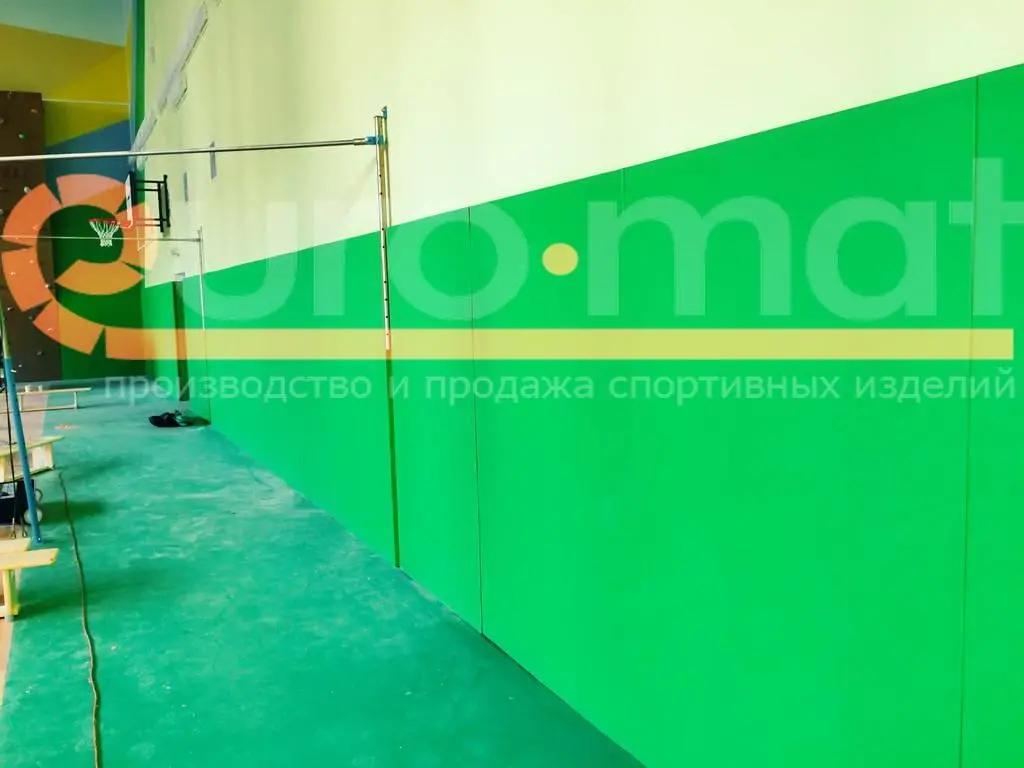 Синие стеновые протекторы на стене спортзала с жёлтыми колоннами и паркетным полом