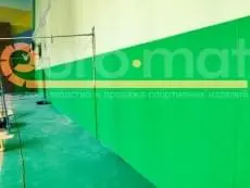 Зелёные стеновые протекторы вдоль стены спортивного зала с баскетбольным кольцом и скалодромом