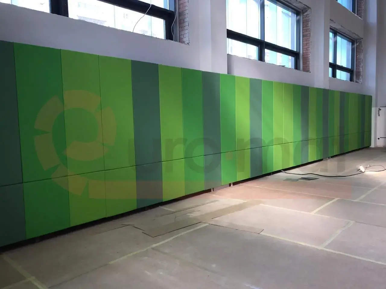Зелёные стеновые протекторы в полоску разных оттенков вдоль длинной стены спортзала