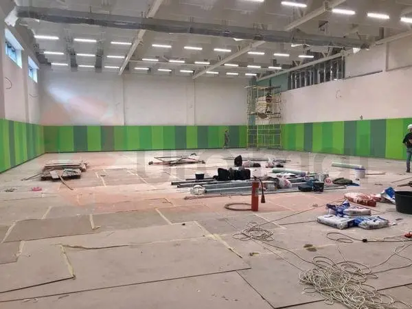 Монтаж зелёных стеновых протекторов в спортзале — чередование тёмно-зелёных и салатовых панелей