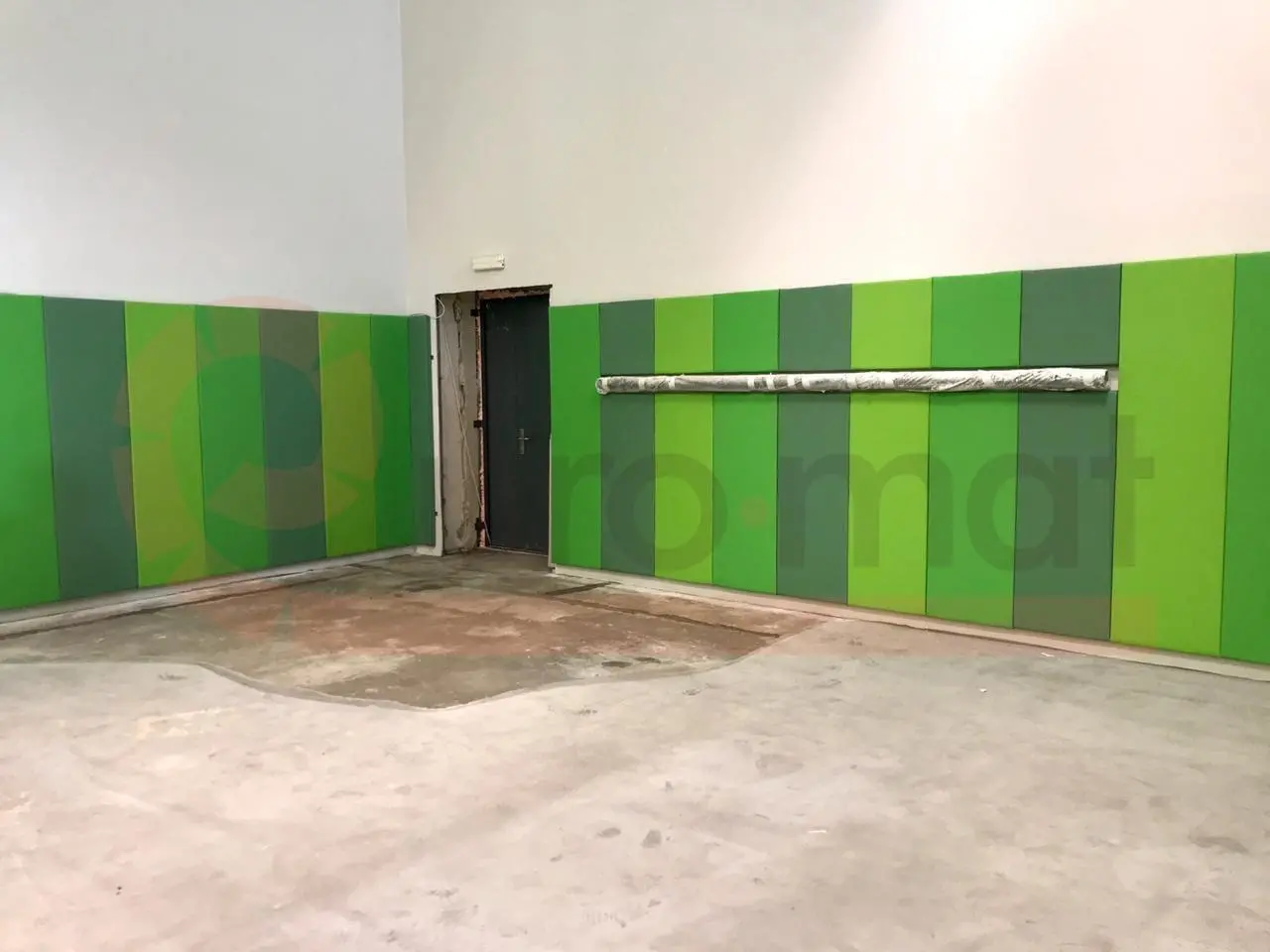 Стеновые протекторы в углу спортзала — зелёные панели двух оттенков вокруг дверного проёма