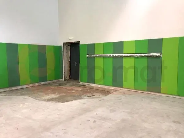 Стеновые протекторы в углу спортзала — зелёные панели двух оттенков вокруг дверного проёма