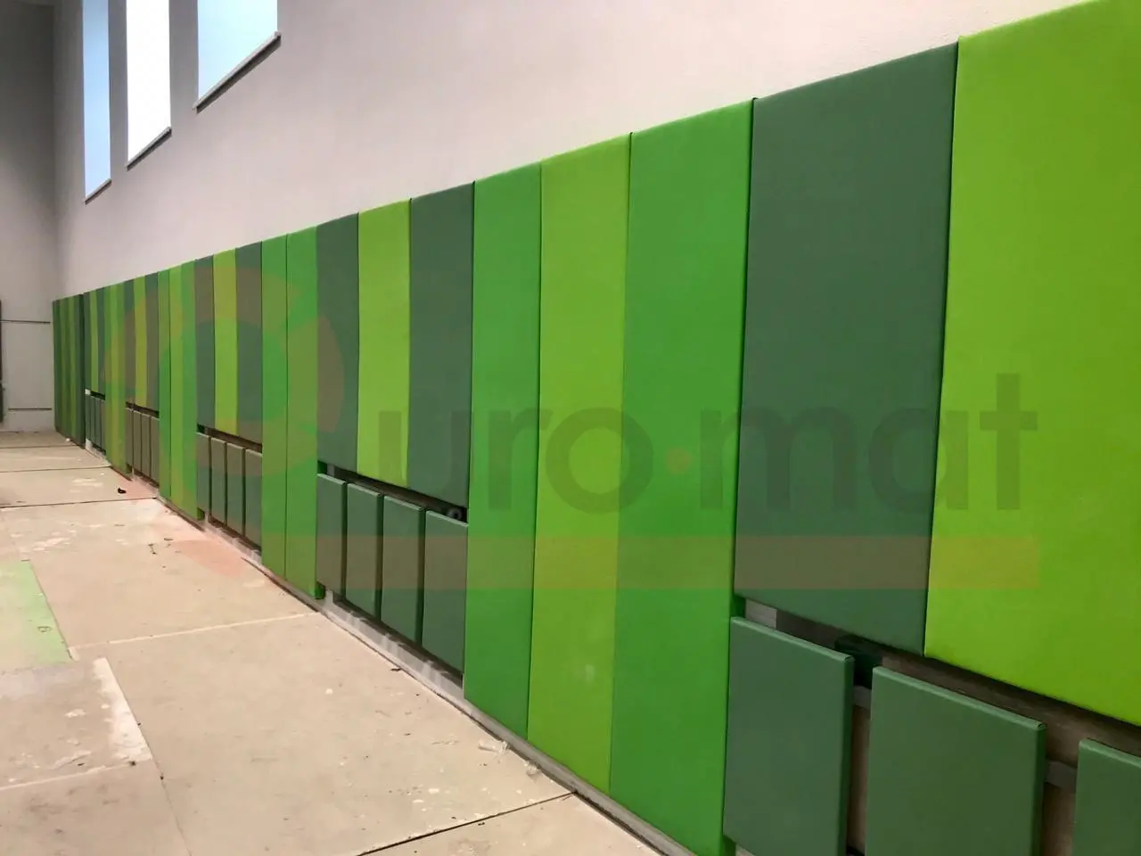 Зелёные стеновые протекторы вдоль стены спортзала крупным планом — панели закрывают батареи отопления