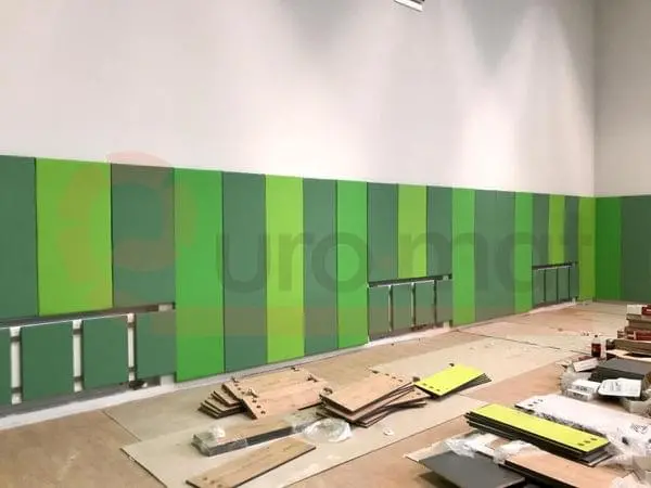 Стеновые протекторы зелёного цвета вдоль длинной стены спортзала — вид сбоку, идёт ремонт