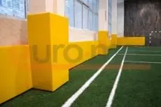 Жёлтые стеновые протекторы на колоннах в спортзале с искусственным газоном