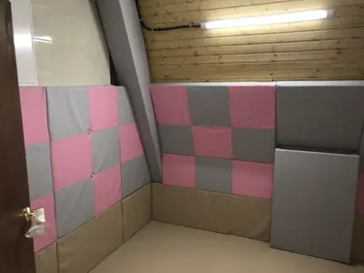 Розово-серые стеговые стеновые протекторы в шахматном порядке и белые маты в детской комнате бревенчатого дома