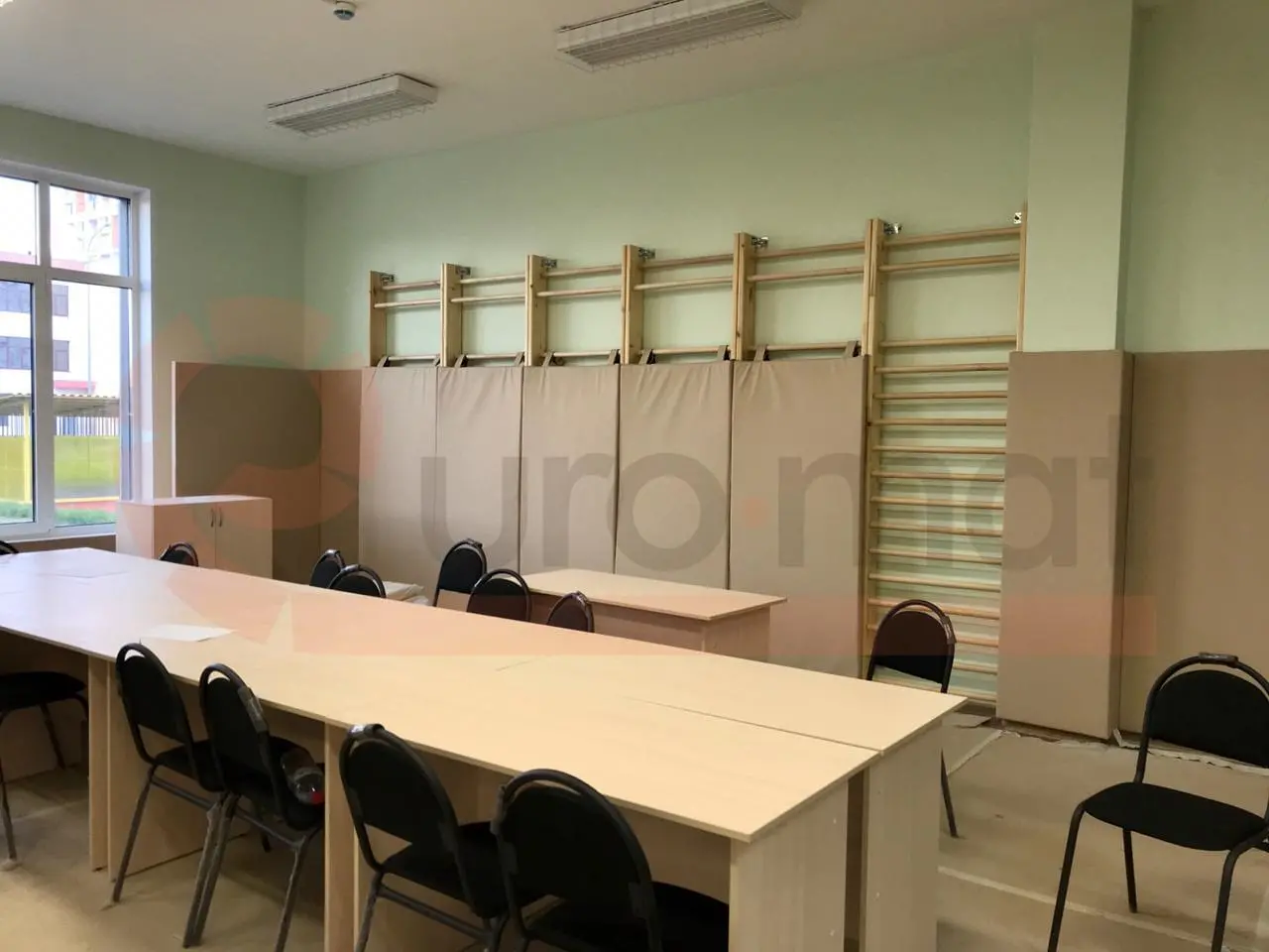 Бежевые стеновые протекторы в спортзале детского сада со шведскими стенками и столами