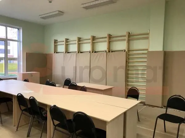 Бежевые стеновые протекторы в спортзале детского сада со шведскими стенками и столами