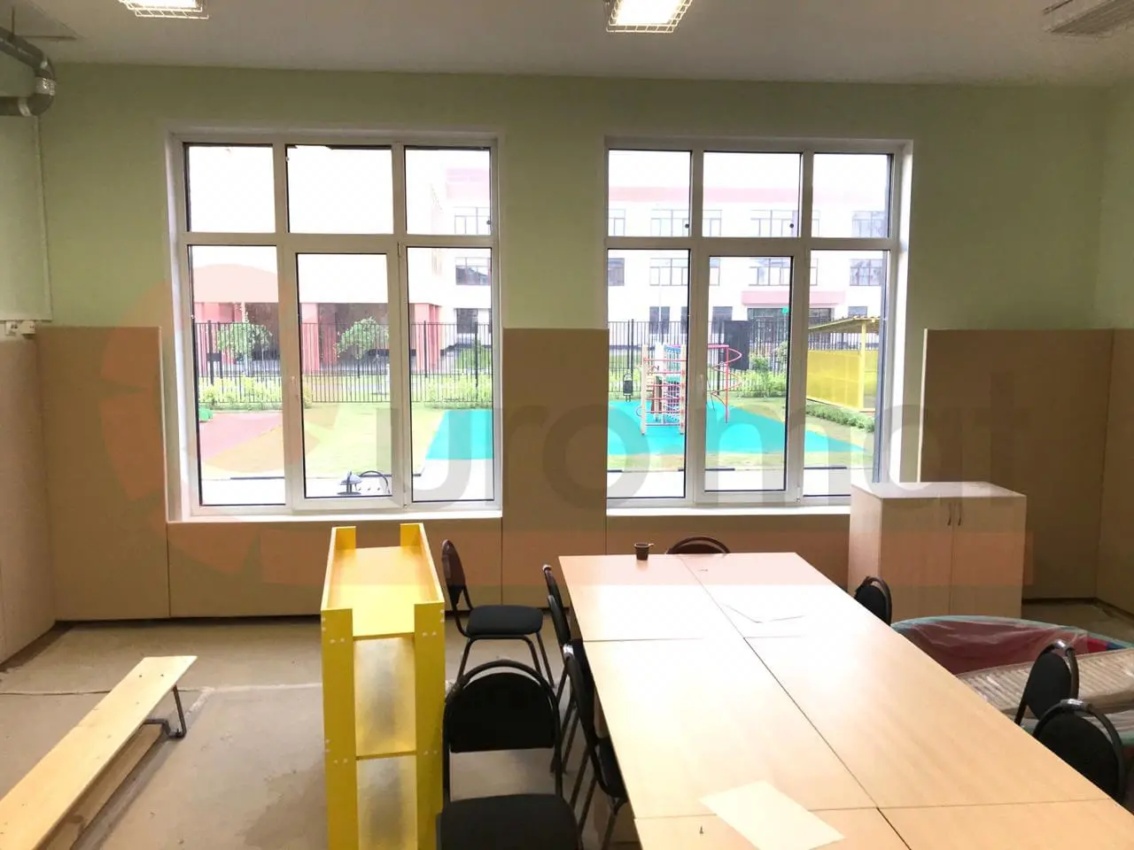 Бежевые стеновые протекторы под окнами спортзала детского сада с видом на детскую площадку