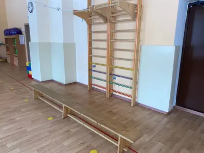 Светло-зелёные стеновые протекторы возле гимнастической скамьи и шведской стенки в детском саду