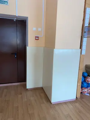 Бежевые угловые протекторы на колонне возле выхода в спортзале детского сада с мячами