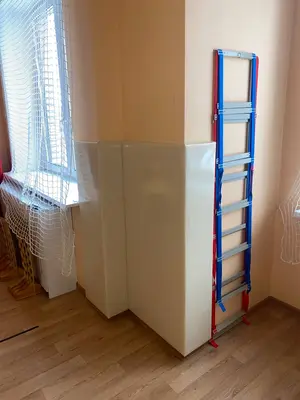 Белые стеновые протекторы на колонне возле окна с радиатором в спортзале детского сада