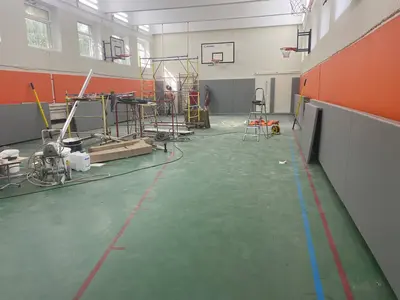 Монтаж двухуровневых оранжево-серых протекторов рабочими на лесах в спортзале Люберцы