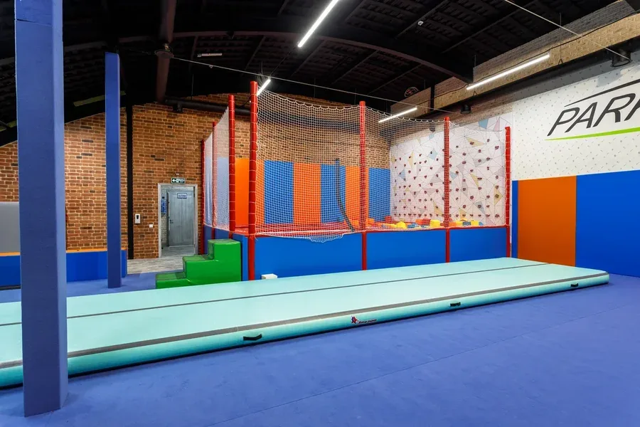 Полный вид зала гимнастики с батутной зоной, скалодромом и защитой