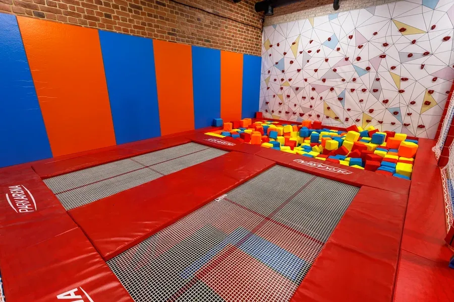 Батутная зона Park Arena с красной обивкой батутов, поролоновой ямой с цветными кубиками и скалодромом