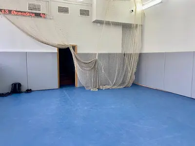 Серые протекторы на стенах спортзала футбольной академии с видом на ворота и синий пол