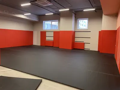 Красно-оранжевые стеновые протекторы и тёмно-серые татами в процессе укладки в зале Новой школы