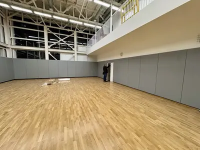 Серые стеновые протекторы на стене спортзала школы Открытие — балкон сверху, рабочий у двери, паркет
