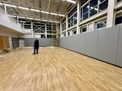 Рабочий монтирует серые стеновые протекторы, строительные леса, широкий зал с балконом