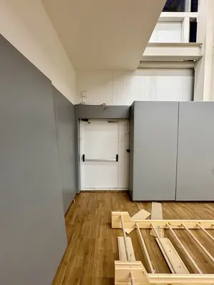 Серые протекторы в углу с дверным проёмом, деревянная монтажная конструкция на полу