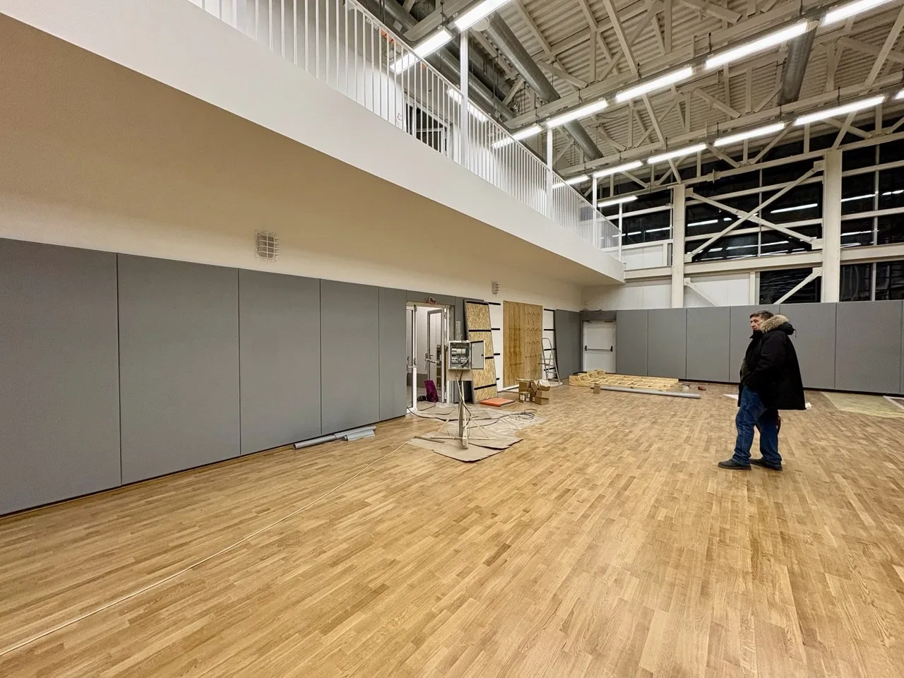 Панорамный вид спортзала — полное покрытие серыми протекторами, паркет, балкон сверху