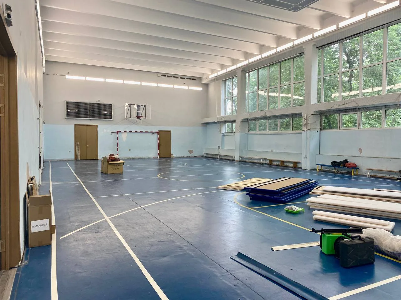 Спортзал школы №630 до установки протекторов — голые светло-голубые стены и материалы на полу