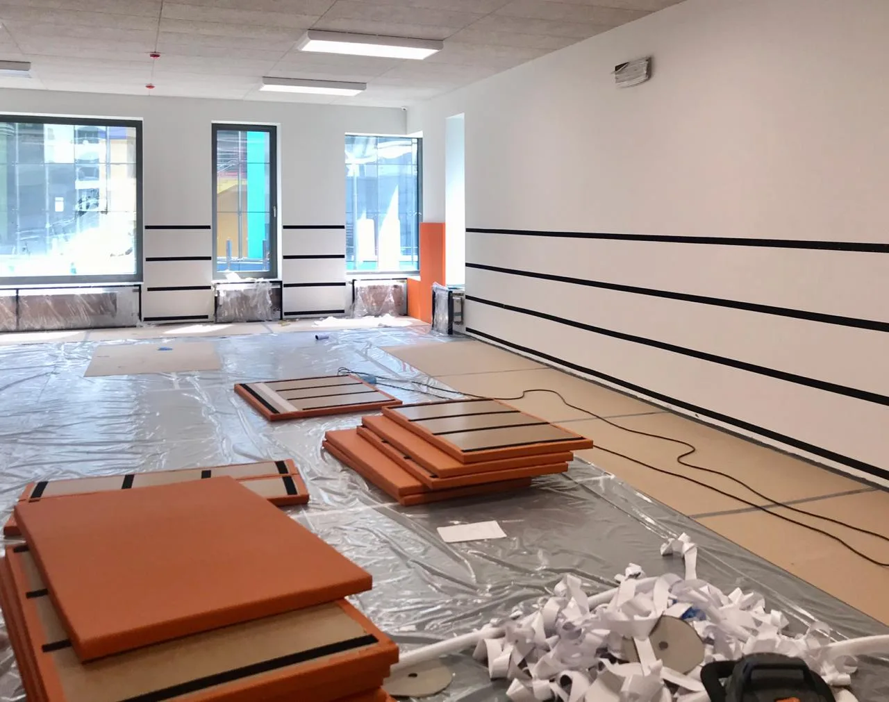 Оранжевые стеновые протекторы на полу с полосами велькро, подготовка стен к монтажу в школе Снегири